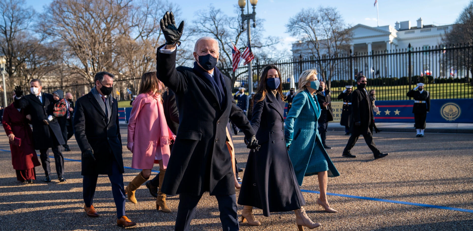 President Biden in a group waving while walking outside the White House